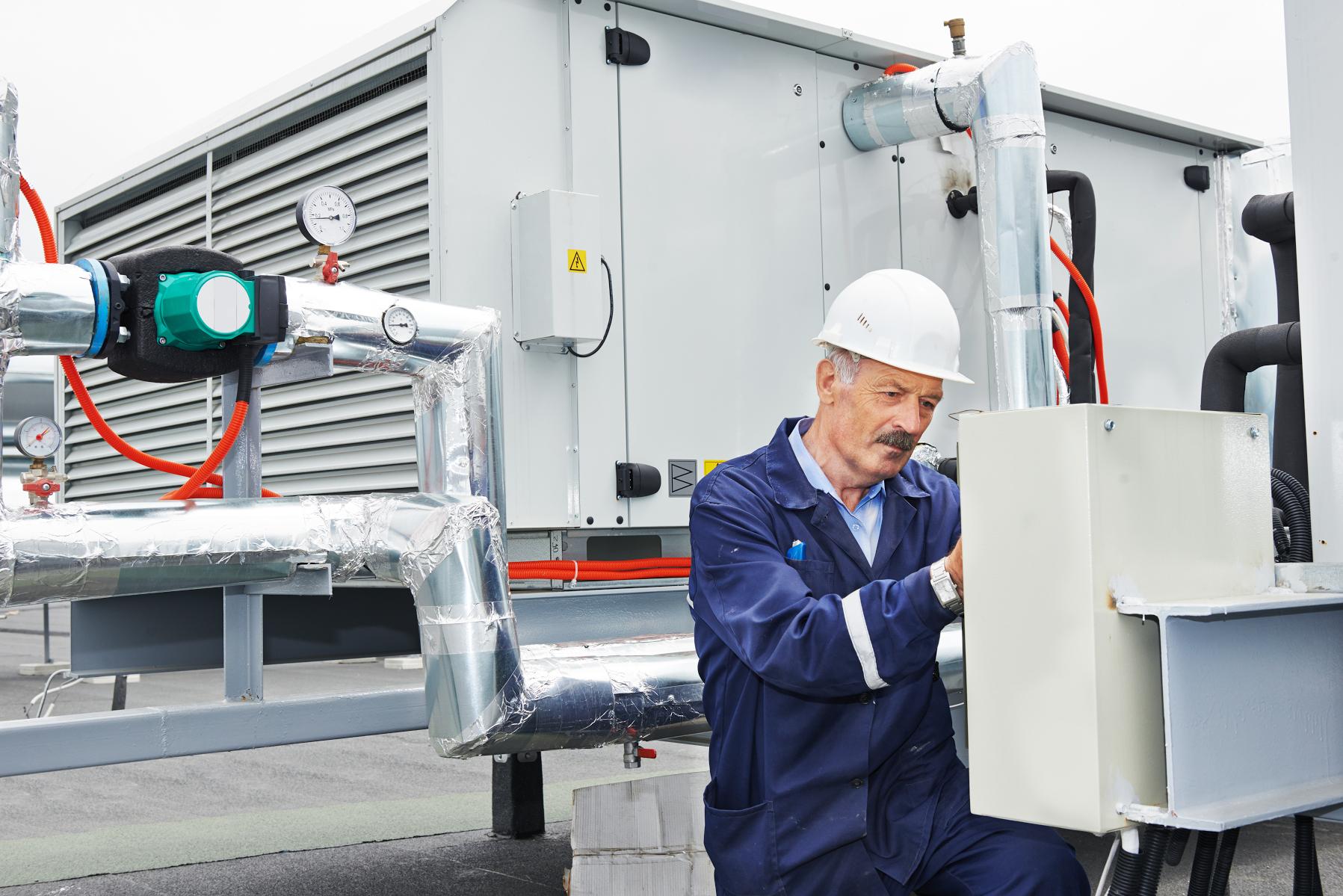 man working on fixing HVAC system on roof