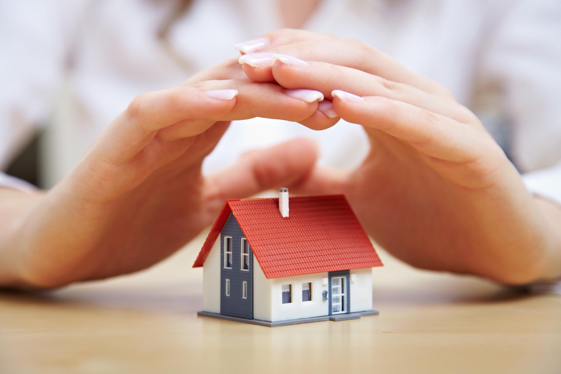 hands hovering over a tiny model house