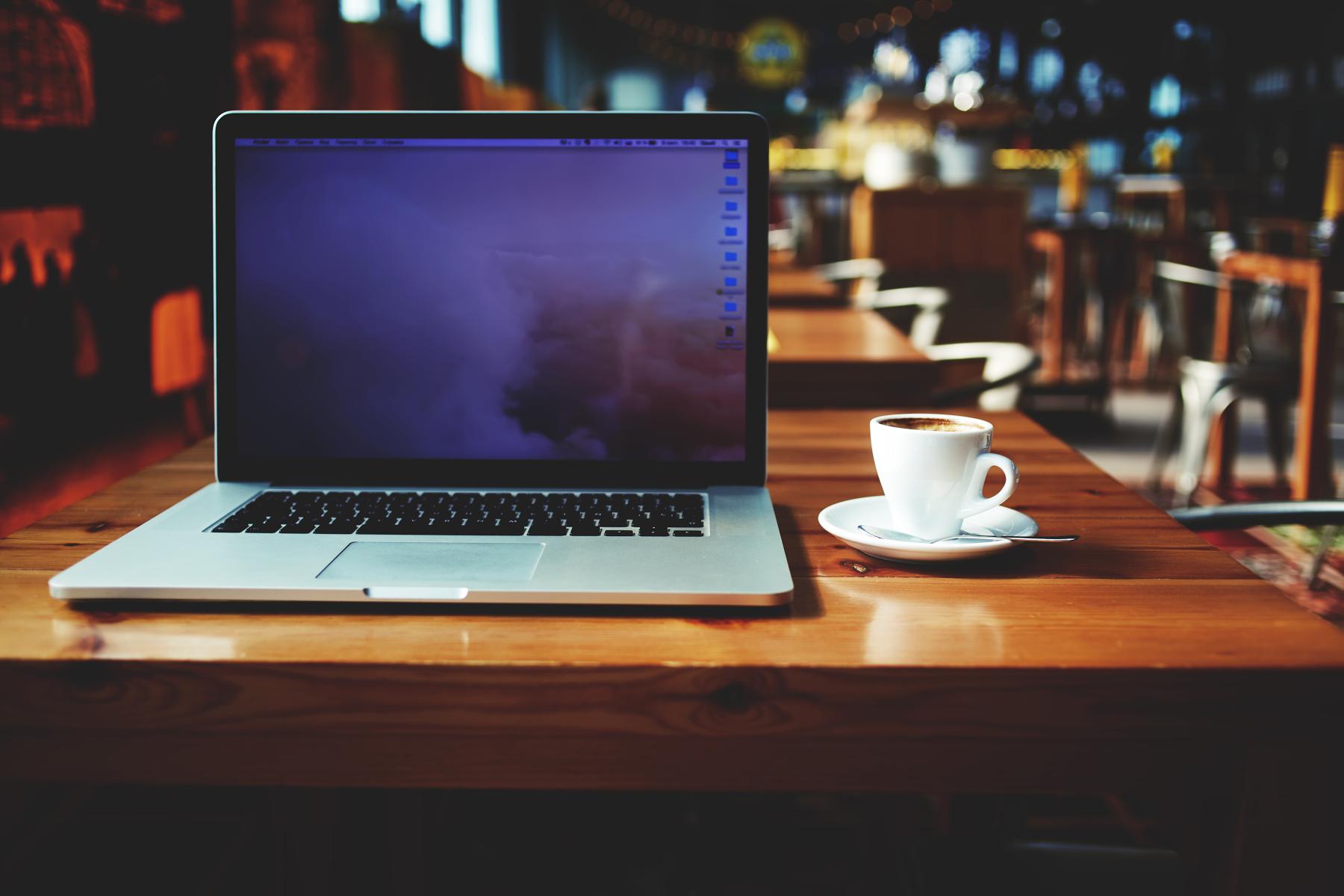 laptop and cup of coffee on table at cafe