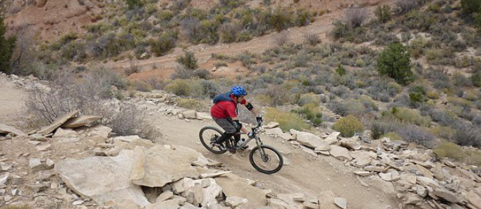 man mountain biking down hill