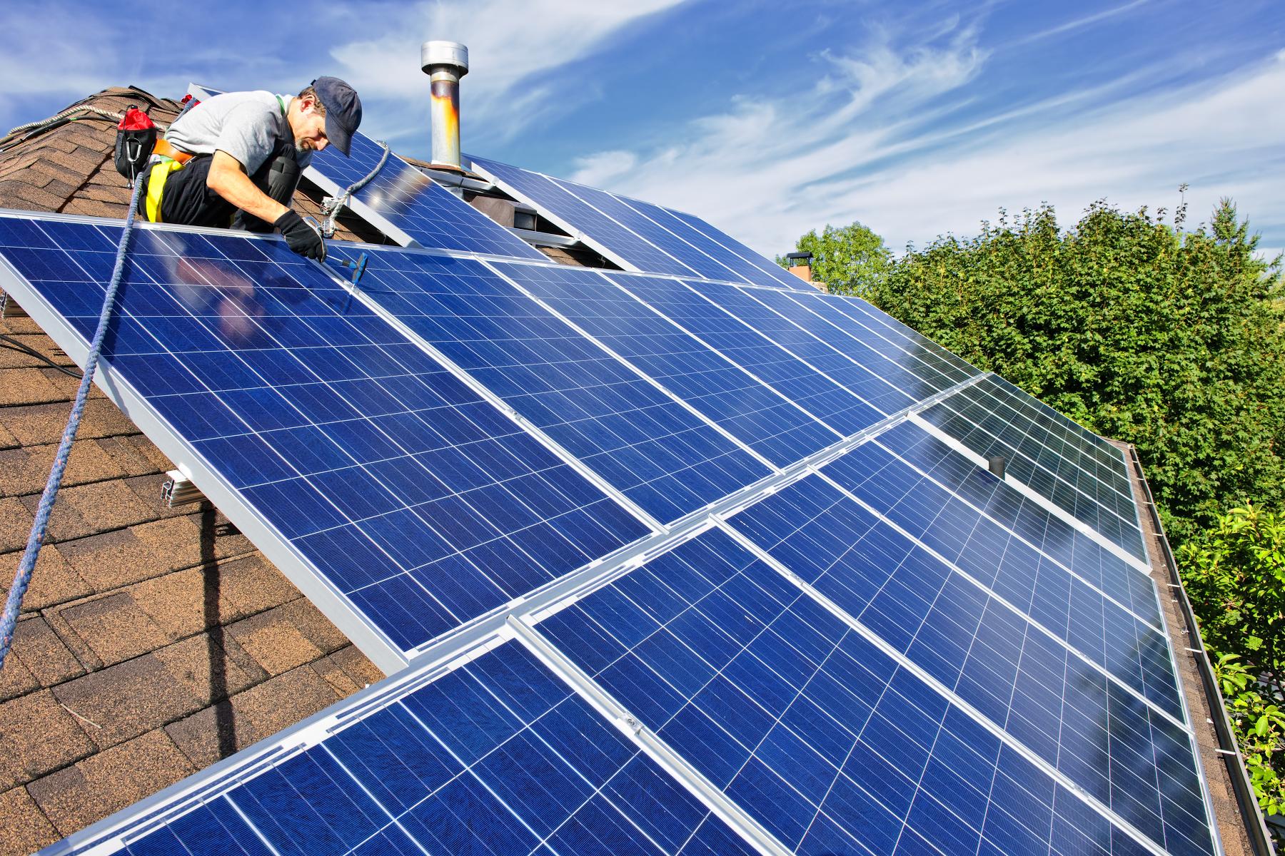 man installing solar panels on roof