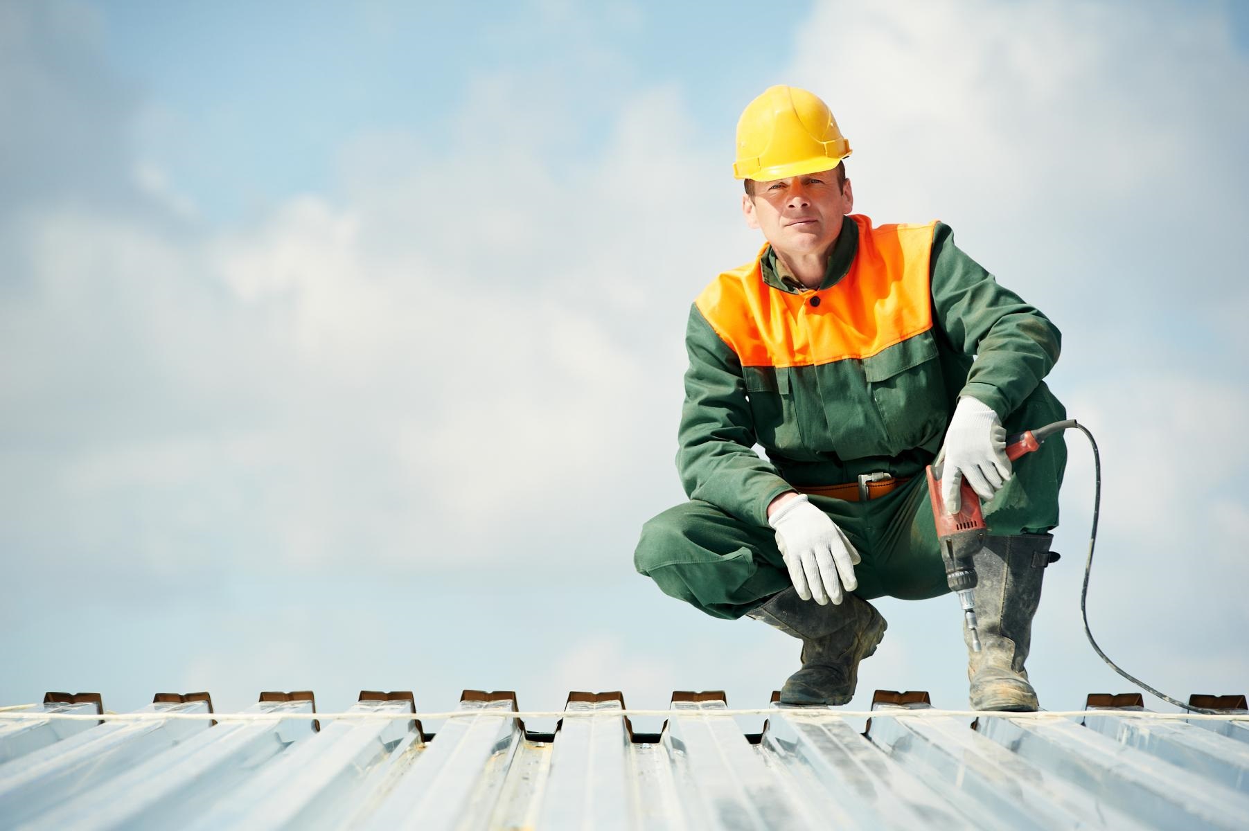 man on the roof with a drill and hard hat